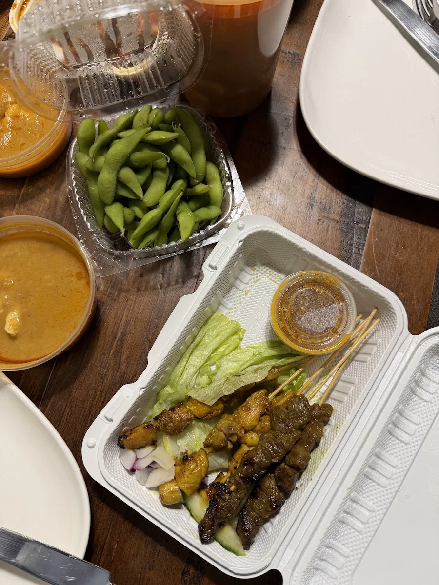 Skewers, sauces and vegetable sides in takeaway containers